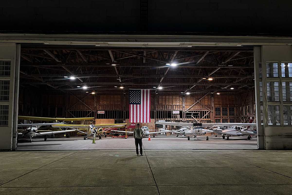 Person standing in front of helicopter garage with an american flag for a blog about federal aviation regulations
