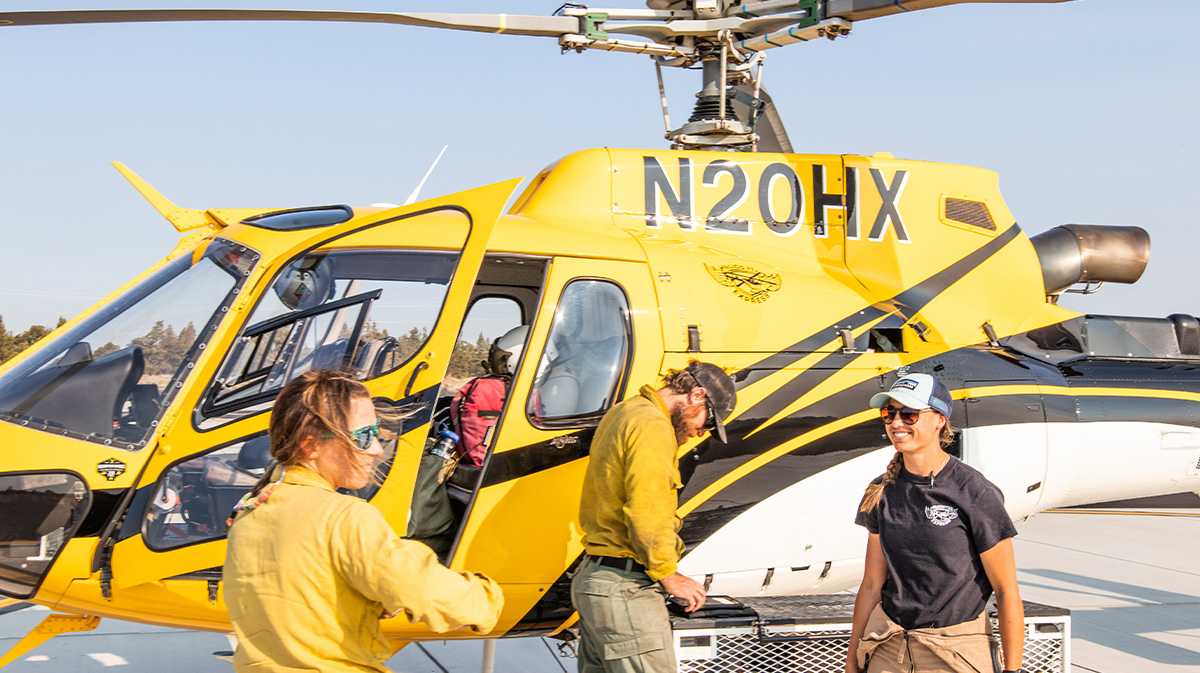 heli pilots around helicopter talking for a blog about low time pilot jobs
