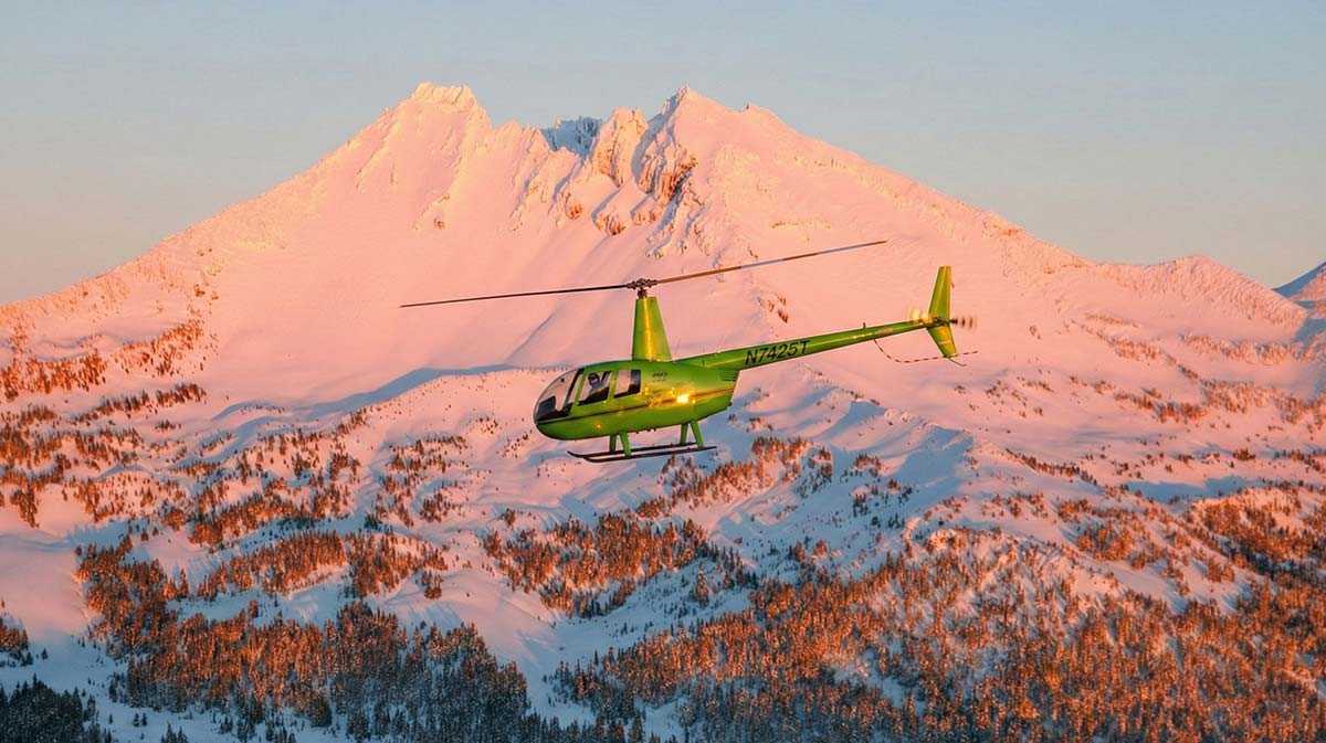 helicopter flying against sunset mountain backdrop for a blog about Why the Altitude of Bend, Oregon Challenges and Strengthens Every Pilot in Training