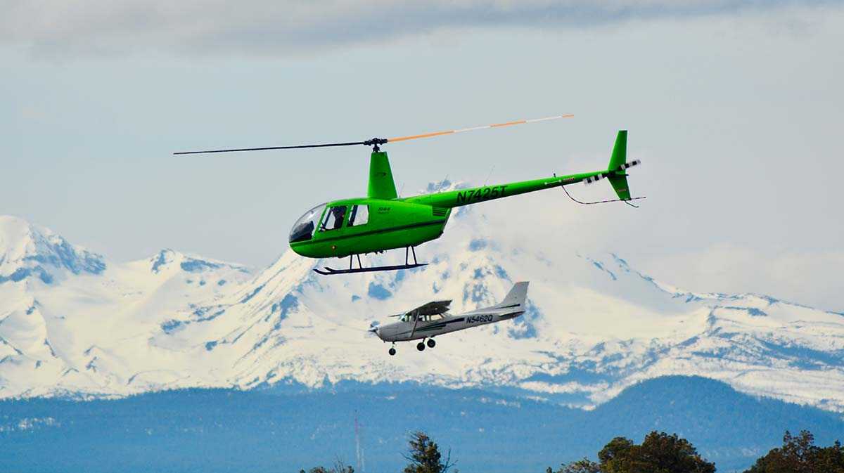 helicopter and airplane flying side by side against snowy mountains for a blog about the future of aviation